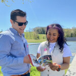 A man and a woman look at the Official Guide to the Berkshires booklet with smiles on their faces in the bright sunshine of the Clark Art.